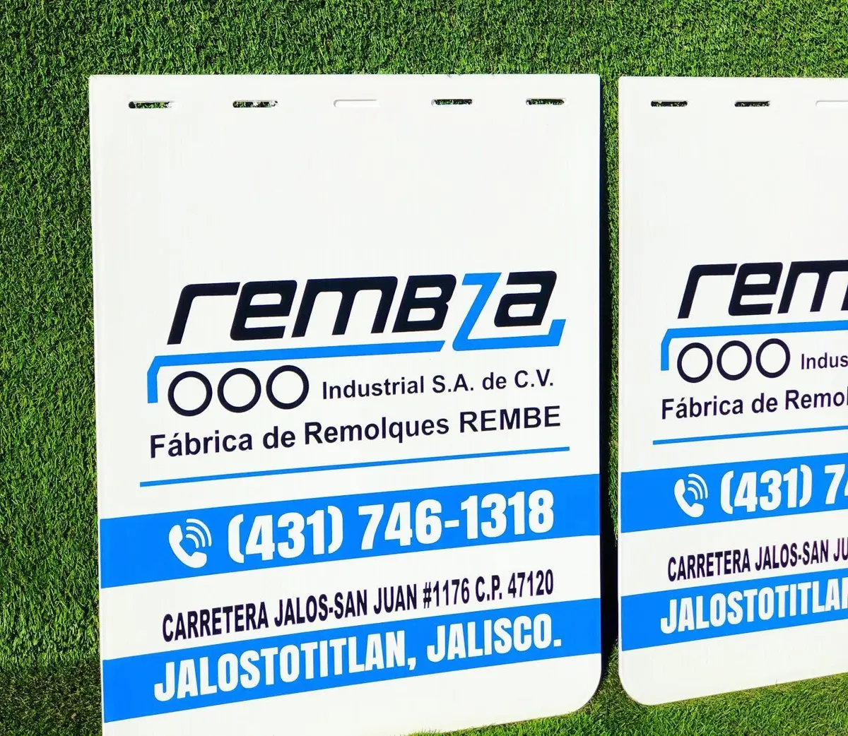 Loderas blancas con logotipo de una fábrica de remolques, teléfono y domicilio en franja azul