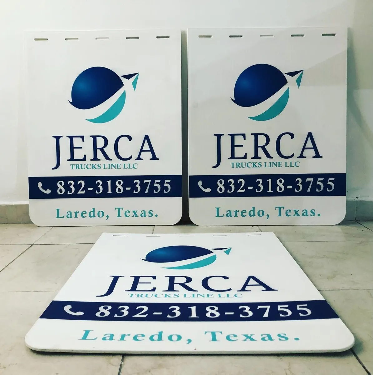 Tres loderas blancas con logotipo azul de una línea de camiones, teléfono y ciudad